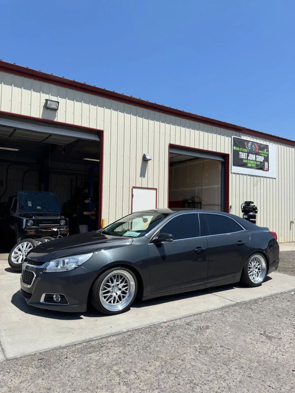 Bagged Chevy Malibu in front of the shop