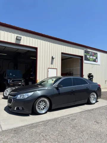Bagged Chevy Malibu in front of the shop