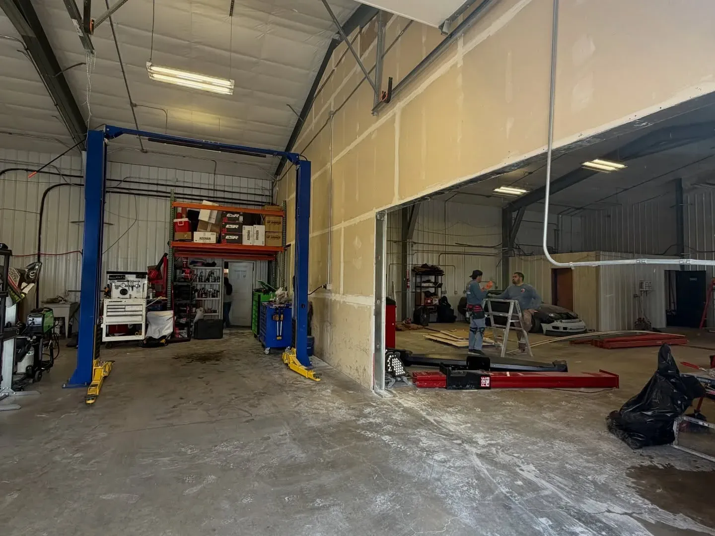 Wide view of the shop interior with two mechanics
